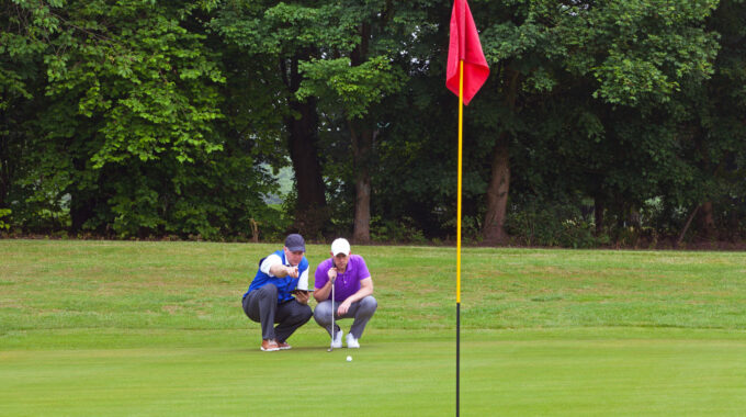 Golfer and caddy putting green